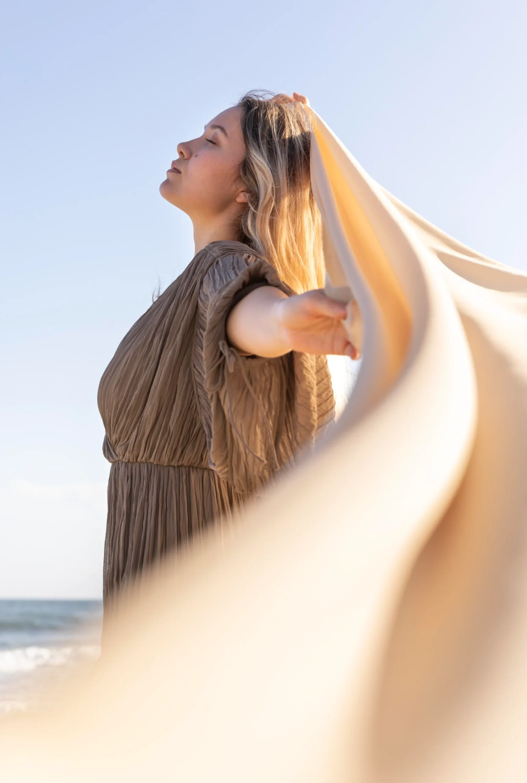 Woman relaxing by the ocean, feeling refreshed and free.